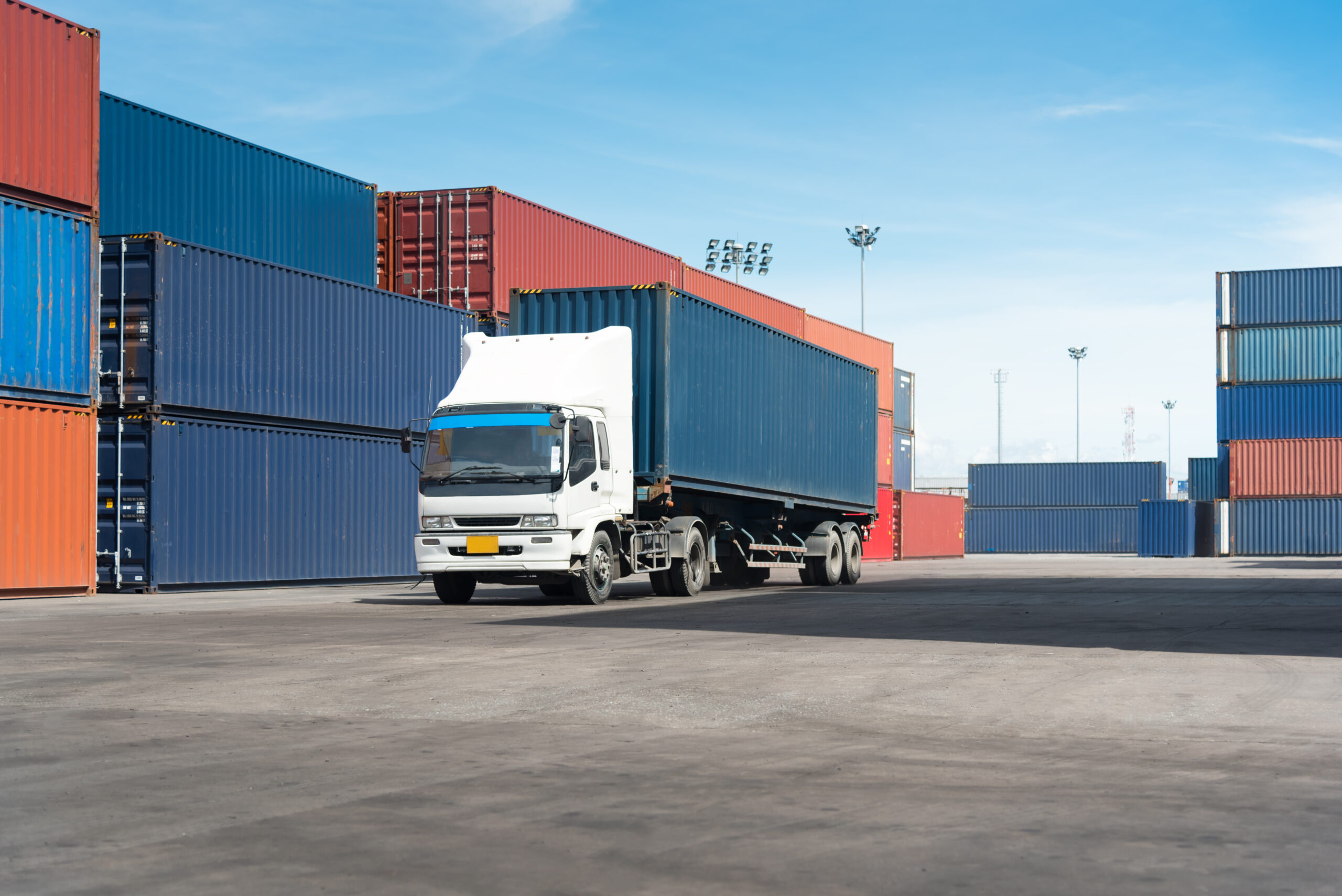 truck with cargo container on road in shipping yard or dock yard against sunrise